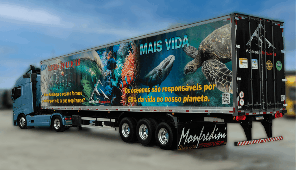 Caminhão azul da Monfredini Transportes com trailer ilustrado com animais marinhos e mensagem de conservação dos oceanos