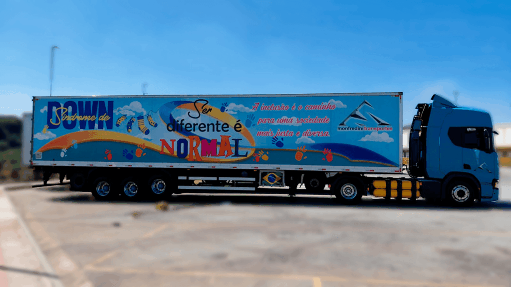 Caminhão da Monfredini Transportes com trailer colorido promovendo inclusão e conscientização sobre a Síndrome de Down