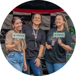 Três colaboradoras sorridentes da Monfredini Transportes segurando placas com as hashtags #SIPAT2024 e #EUFUI. A imagem representa o ambiente de trabalho positivo e as oportunidades de carreira na empresa. Trabalhe conosco!